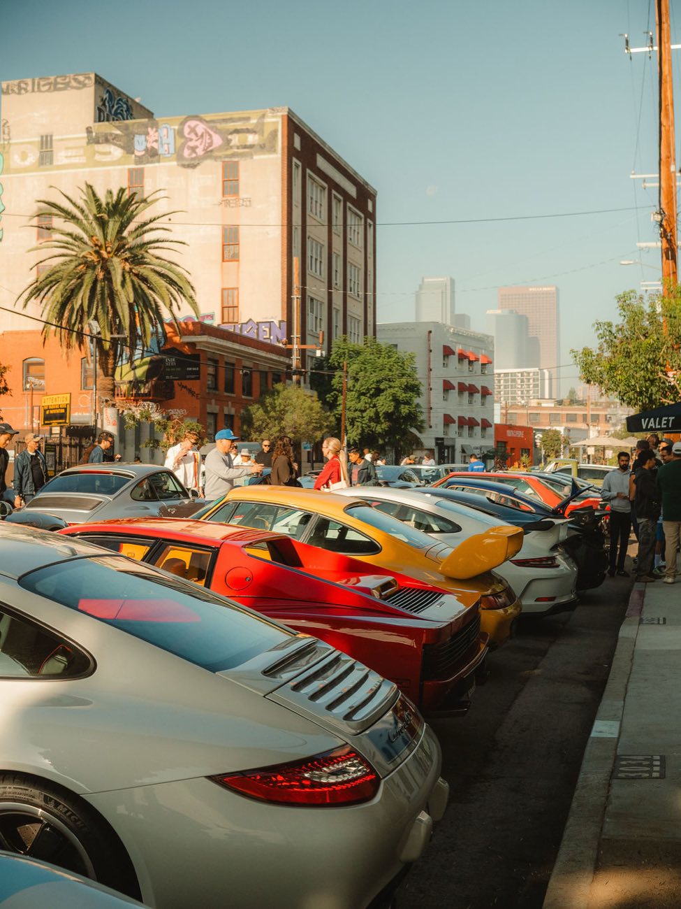 A row of Porsches lined up at Morning Octane with the Los Angeles skyline behind