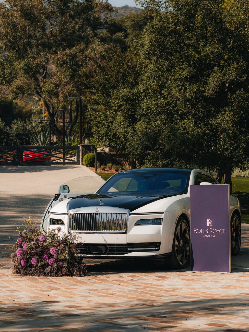 A Rolls-Royce Spectre beside Rolls-Royce Motor Cars signage at the At Home with Rolls-Royce private event